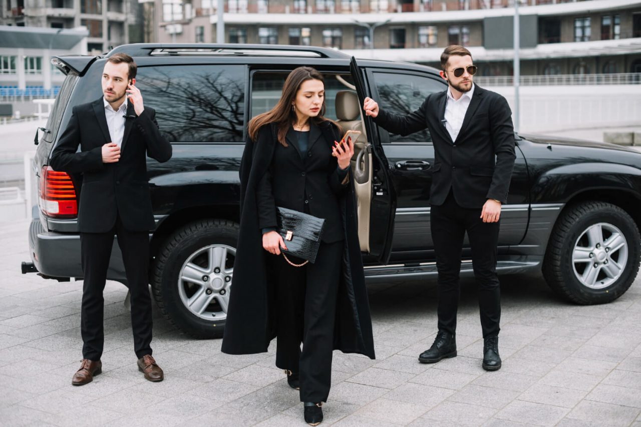 A close protection team standing in front of vehicles, dressed in professional attire, ready to ensure security and safety